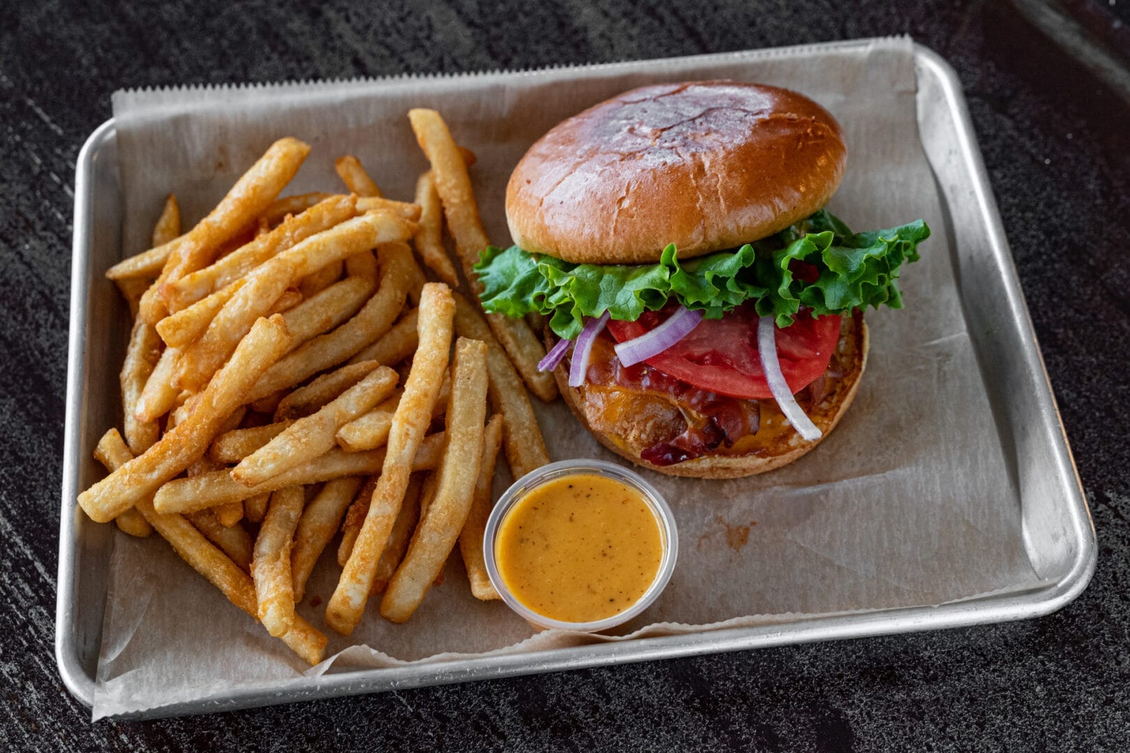 Deluxe chicken sandwich with bacon, cheddar, lettuce, tomato, onion, and Station Sauce served on a fresh bun.